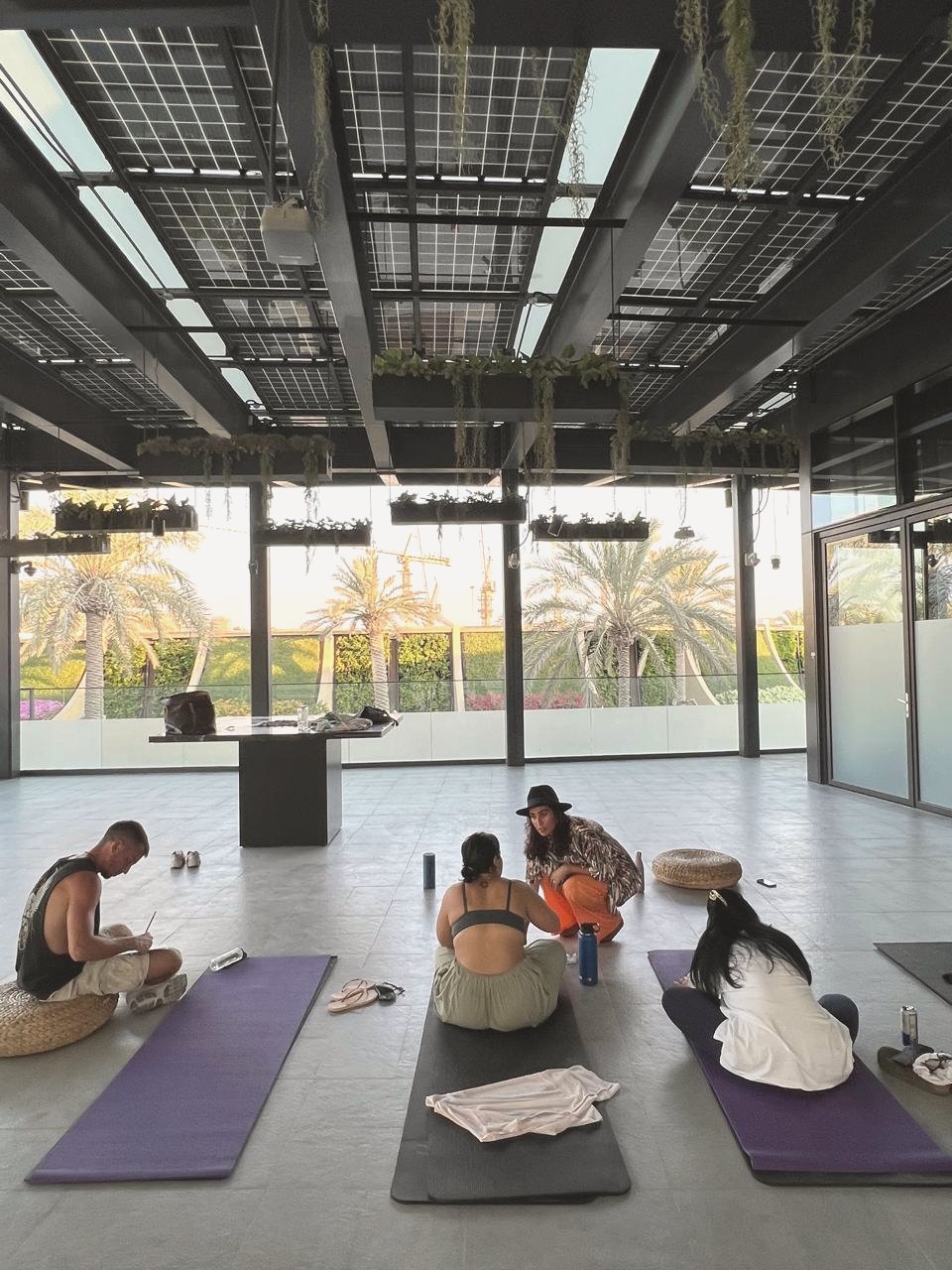 Shazia sitting with a small group on mats in an open-air rooftop space at sunset