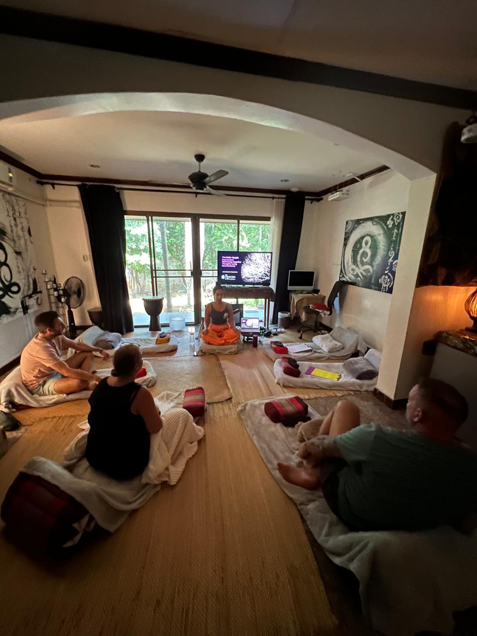 A small group in a circle on cushions during a guided session